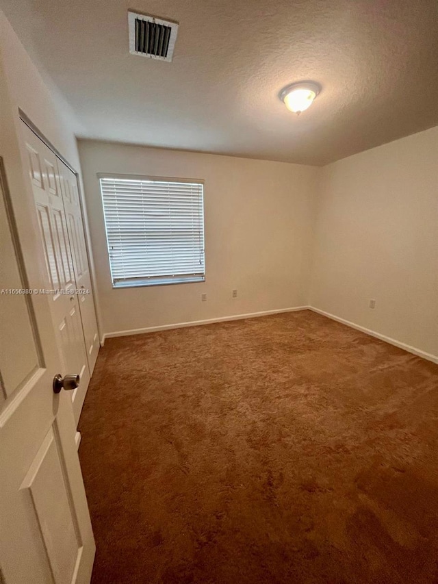 carpeted empty room with a textured ceiling