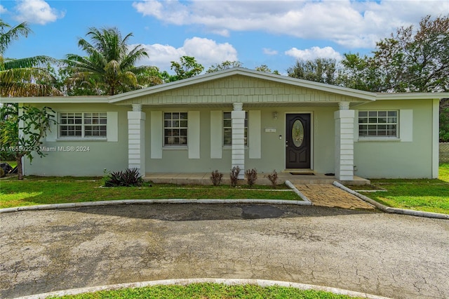 single story home featuring a front lawn and covered porch