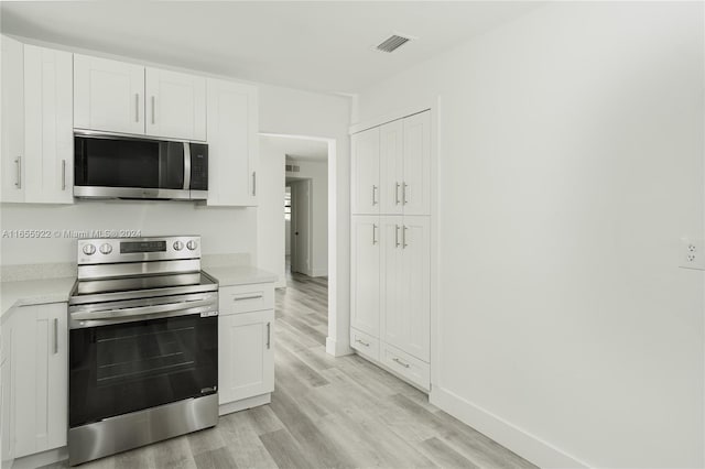 kitchen featuring white cabinets, appliances with stainless steel finishes, and light hardwood / wood-style flooring