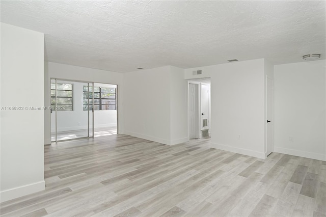 spare room with a textured ceiling and light hardwood / wood-style floors