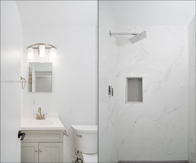 bathroom featuring vanity, toilet, and tiled shower