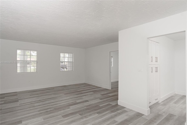 empty room featuring a textured ceiling and light hardwood / wood-style flooring