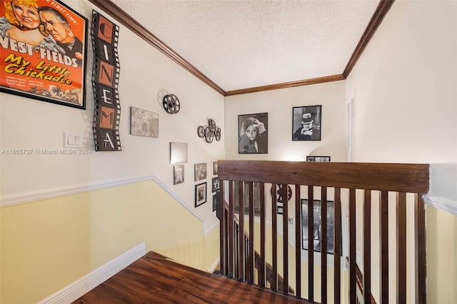 corridor with a textured ceiling, ornamental molding, and hardwood / wood-style floors