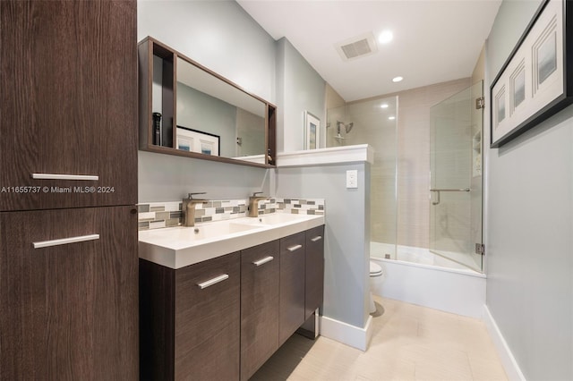 full bathroom with tile patterned floors, toilet, bath / shower combo with glass door, decorative backsplash, and vanity