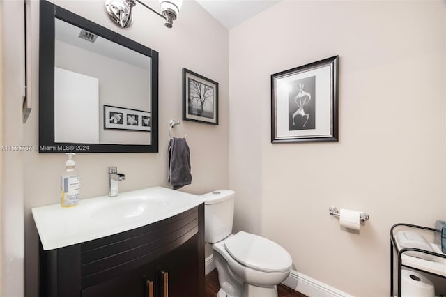 bathroom with vanity, toilet, and hardwood / wood-style floors