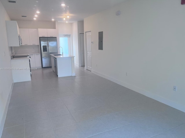 kitchen with light tile patterned floors, stainless steel fridge with ice dispenser, a kitchen island with sink, electric panel, and white cabinets