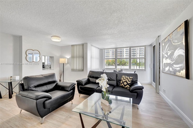 living area featuring a textured ceiling, light wood finished floors, and baseboards