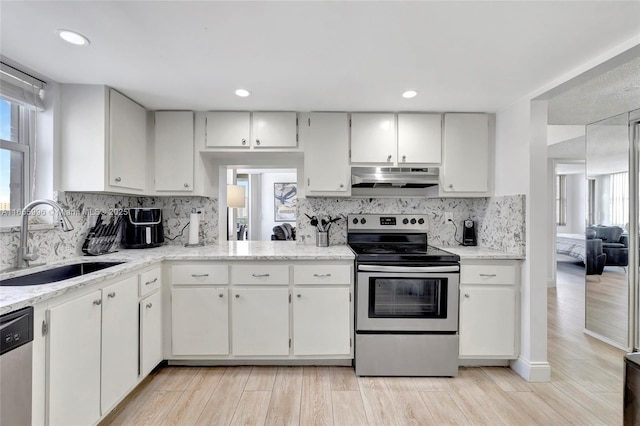 kitchen with under cabinet range hood, a sink, white cabinetry, appliances with stainless steel finishes, and light wood-type flooring