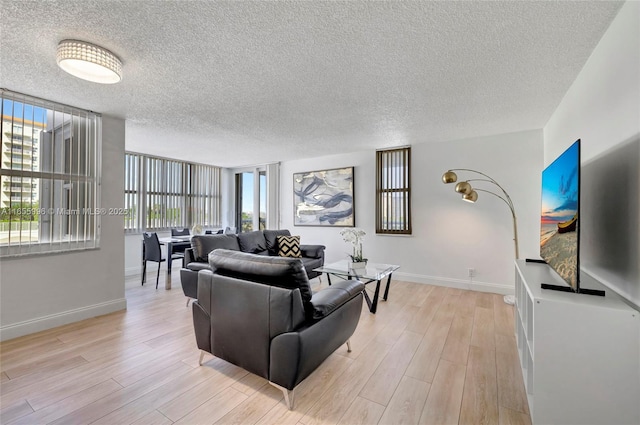 living room featuring a textured ceiling, light wood finished floors, and baseboards