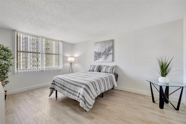 bedroom with a textured ceiling and light wood-type flooring