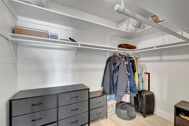 walk in closet with light hardwood / wood-style floors