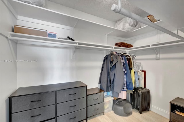 walk in closet with wood finished floors