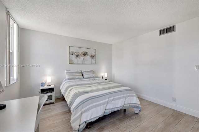 bedroom with a textured ceiling and light hardwood / wood-style flooring