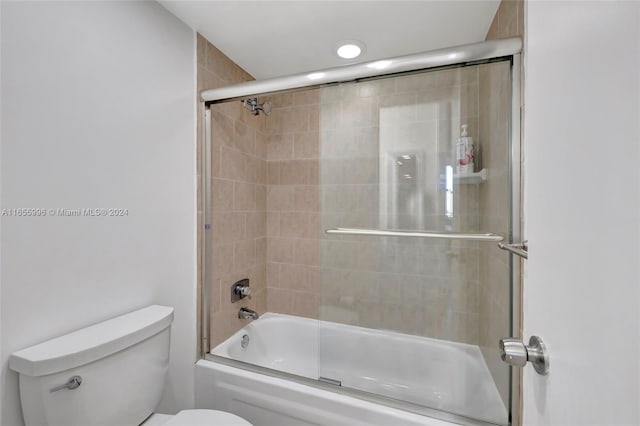 bathroom with toilet and combined bath / shower with glass door