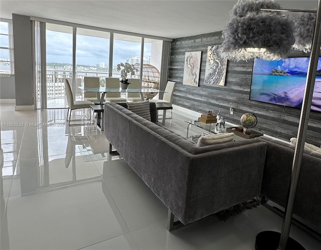 living room with floor to ceiling windows, wallpapered walls, wood walls, an accent wall, and baseboards