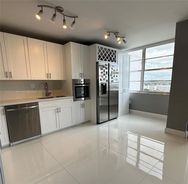 kitchen with light tile patterned floors, white cabinets, a sink, and appliances with stainless steel finishes