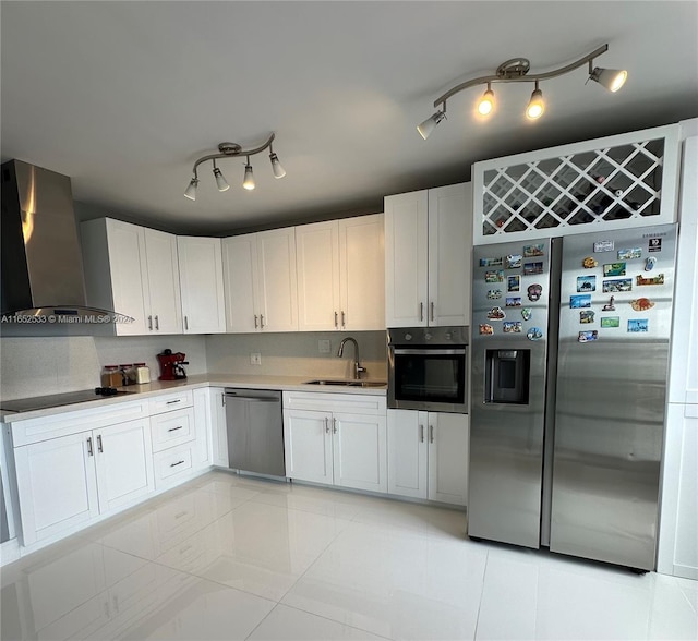 kitchen with wall chimney exhaust hood, stainless steel appliances, a sink, white cabinetry, and rail lighting