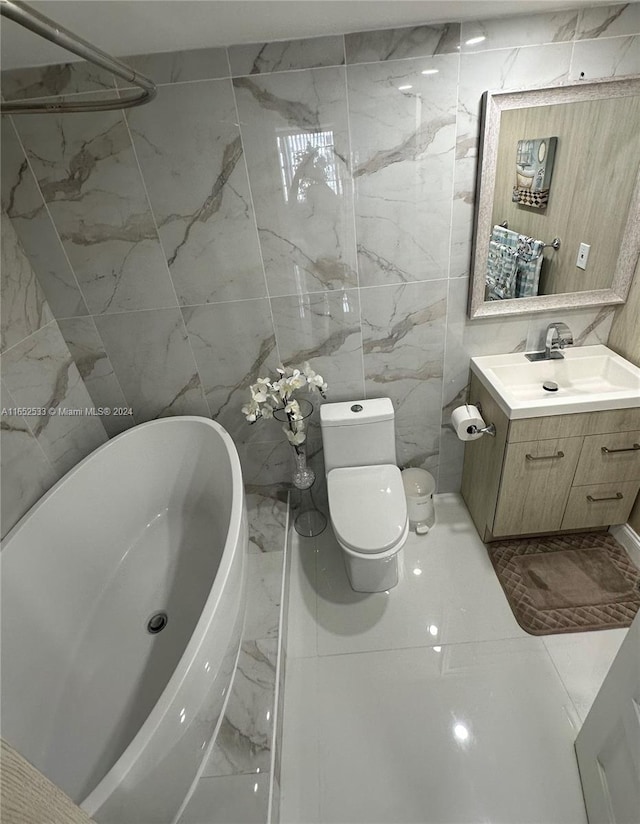 full bathroom with marble finish floor, toilet, vanity, tile walls, and a freestanding tub