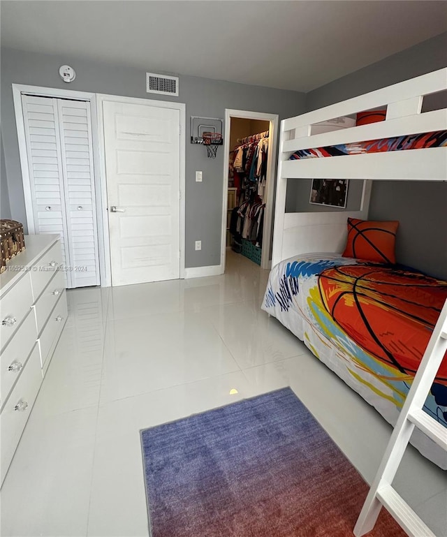 bedroom with a walk in closet, tile patterned flooring, visible vents, and a closet