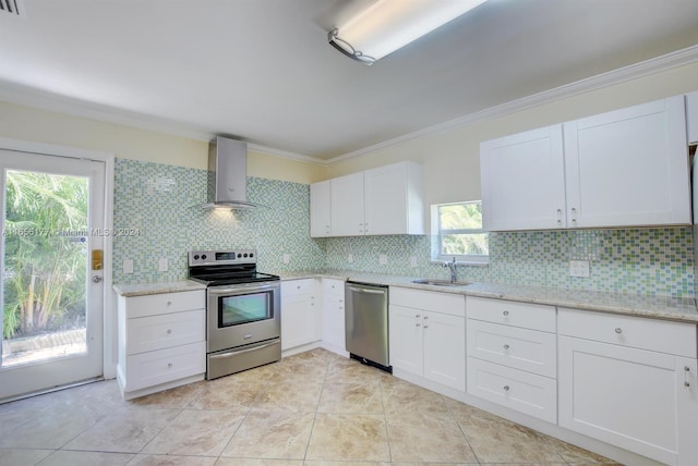 kitchen with a wealth of natural light, stainless steel appliances, white cabinets, and wall chimney range hood