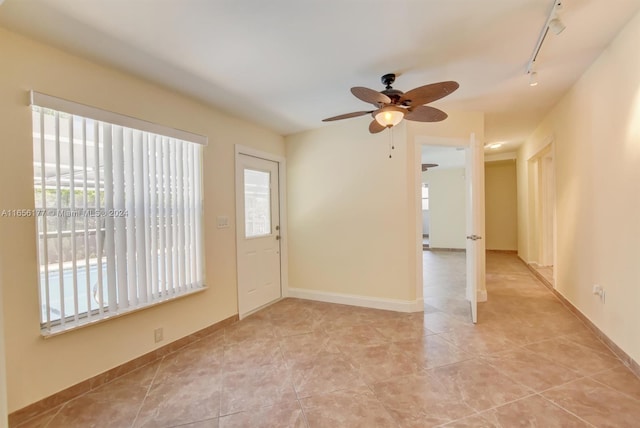 tiled empty room with rail lighting and ceiling fan