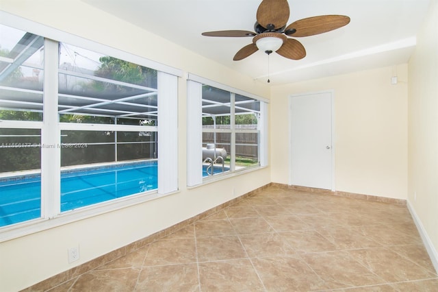 tiled empty room featuring ceiling fan and plenty of natural light