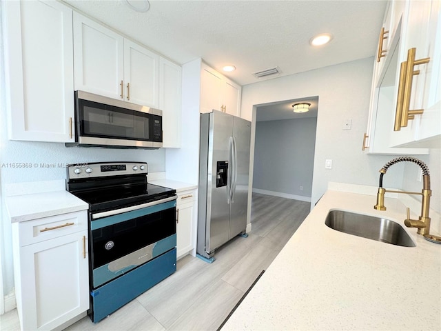 kitchen with appliances with stainless steel finishes, white cabinetry, and sink