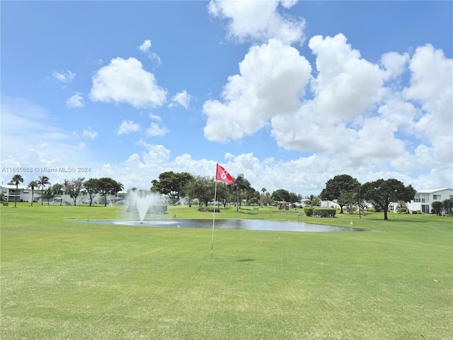 surrounding community with a water view and a lawn