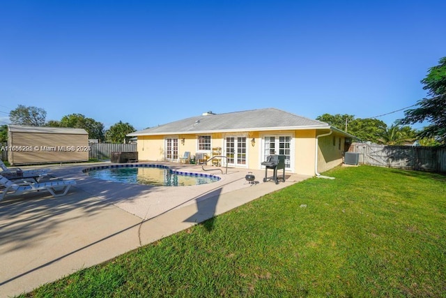 view of swimming pool featuring french doors, a yard, a patio, and central AC unit