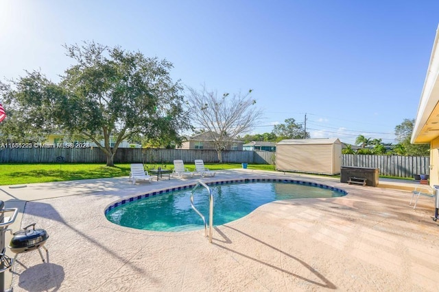 view of swimming pool with a storage unit, a yard, and a patio area