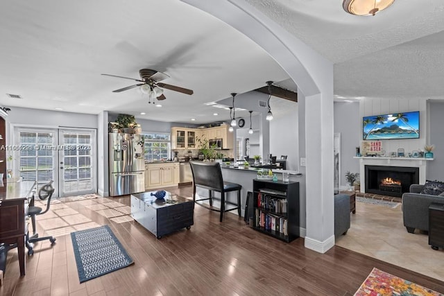 living room with light wood-type flooring, vaulted ceiling, ceiling fan, and a textured ceiling