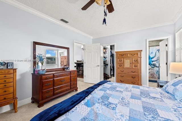 bedroom with ceiling fan, a textured ceiling, ensuite bathroom, and a spacious closet