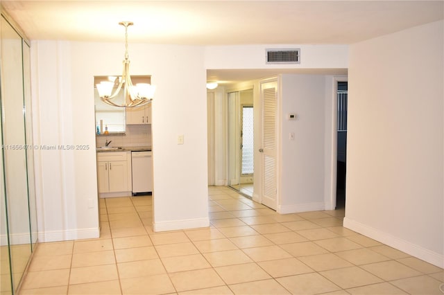 empty room featuring visible vents, a sink, light tile patterned floors, and a chandelier