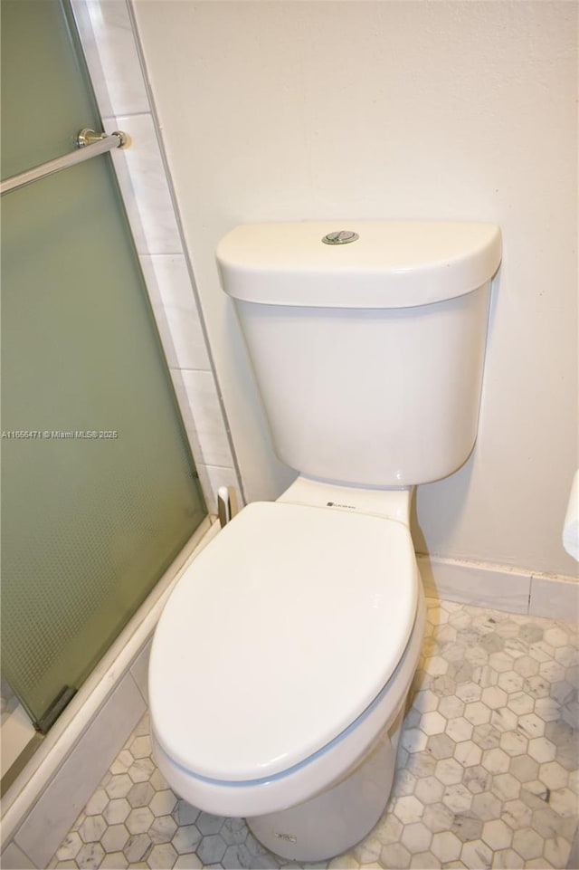 full bathroom featuring toilet, a shower stall, and tile patterned flooring