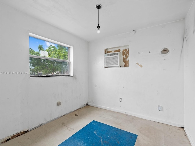 unfurnished room with a wall unit AC and baseboards