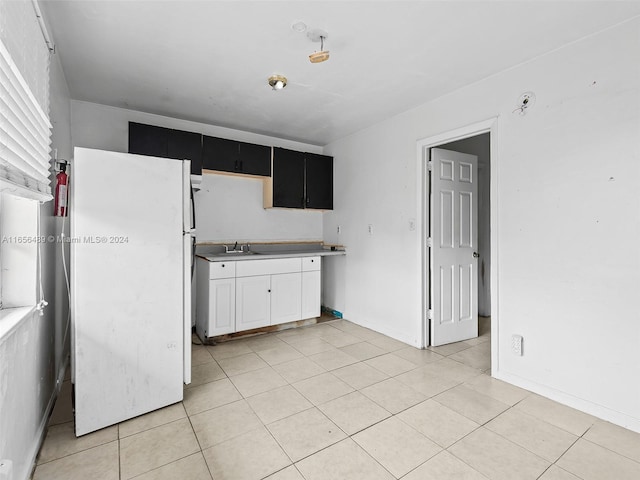 kitchen with white fridge, sink, white cabinetry, and light tile patterned flooring