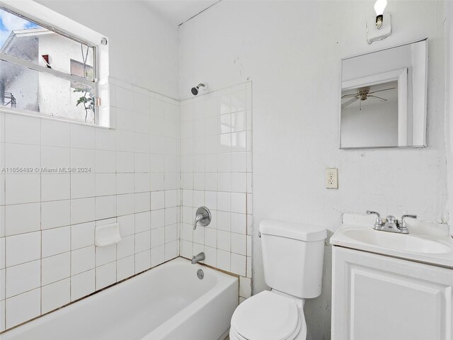 full bathroom with tiled shower / bath, vanity, toilet, and ceiling fan