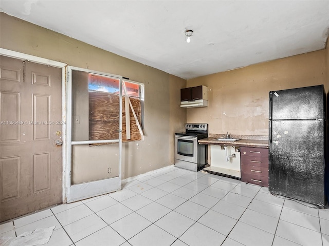 kitchen featuring light tile patterned floors, stainless steel electric stove, light countertops, and freestanding refrigerator