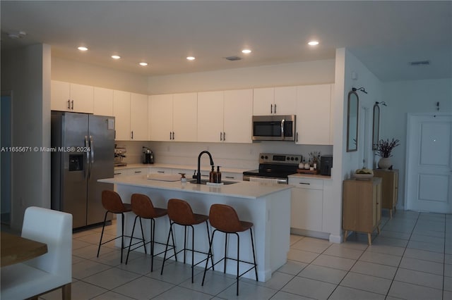 kitchen featuring an island with sink, stainless steel appliances, white cabinetry, and sink