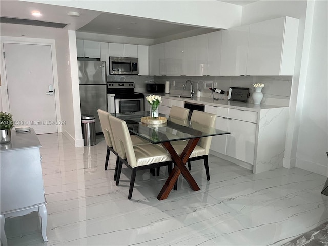 kitchen with stainless steel appliances, sink, decorative backsplash, and white cabinets