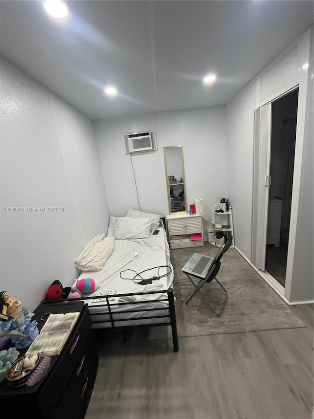 bedroom featuring hardwood / wood-style flooring and a wall mounted AC