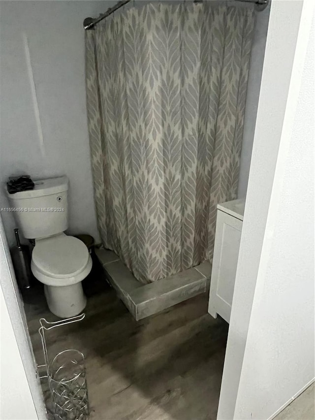 bathroom featuring curtained shower, wood-type flooring, and toilet