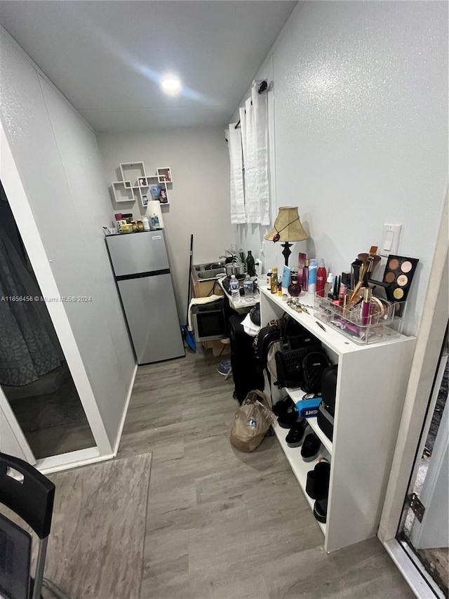 kitchen with white cabinets, stainless steel refrigerator, and light hardwood / wood-style flooring