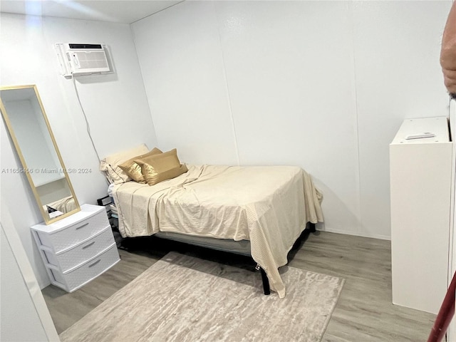 bedroom featuring wood-type flooring and a wall mounted air conditioner