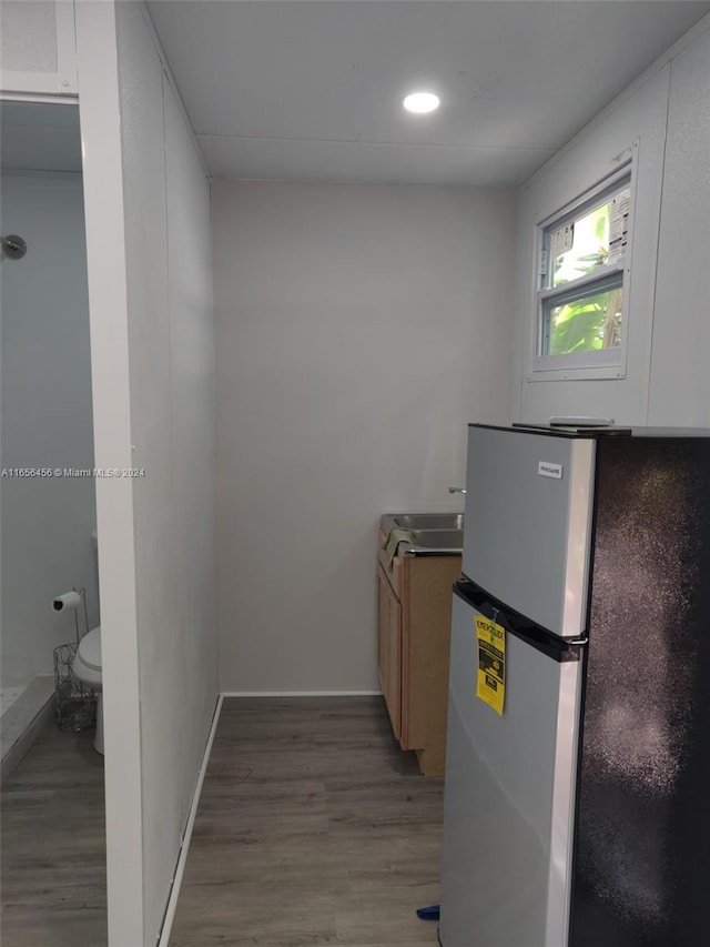 kitchen with light wood-type flooring, sink, and stainless steel refrigerator