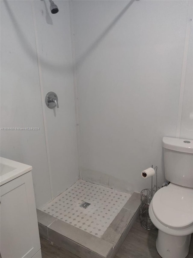 bathroom with walk in shower, hardwood / wood-style floors, vanity, and toilet