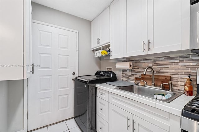 interior space featuring washing machine and clothes dryer, white cabinetry, and sink