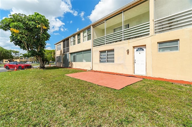 rear view of property featuring a lawn and a patio