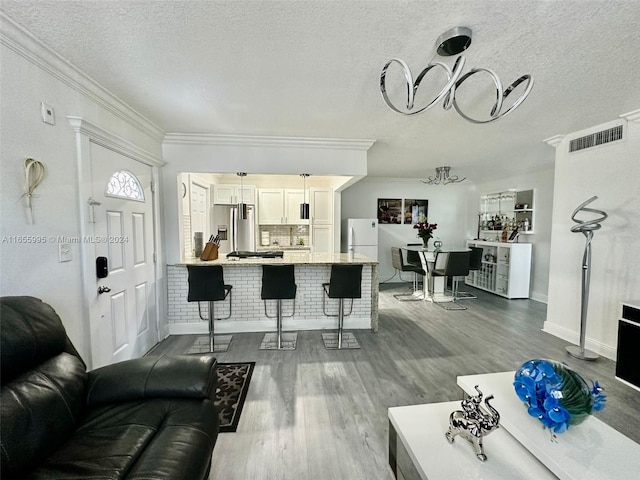 living room with wood-type flooring, crown molding, and a textured ceiling