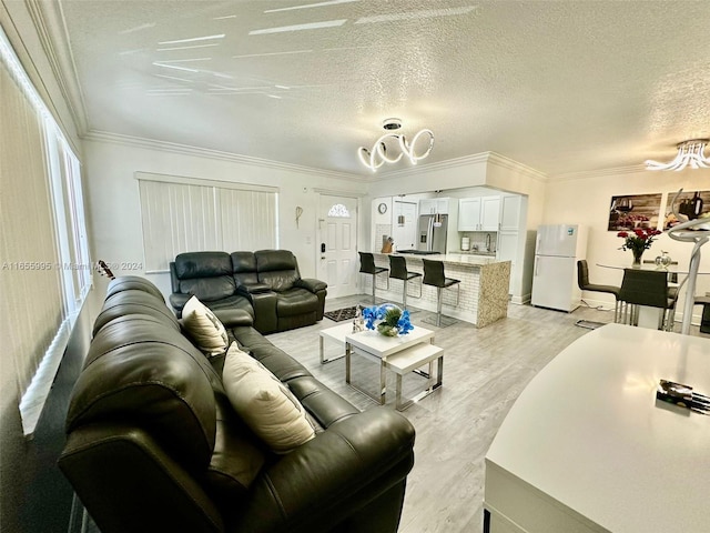 living room with ornamental molding, a textured ceiling, an inviting chandelier, and light hardwood / wood-style floors